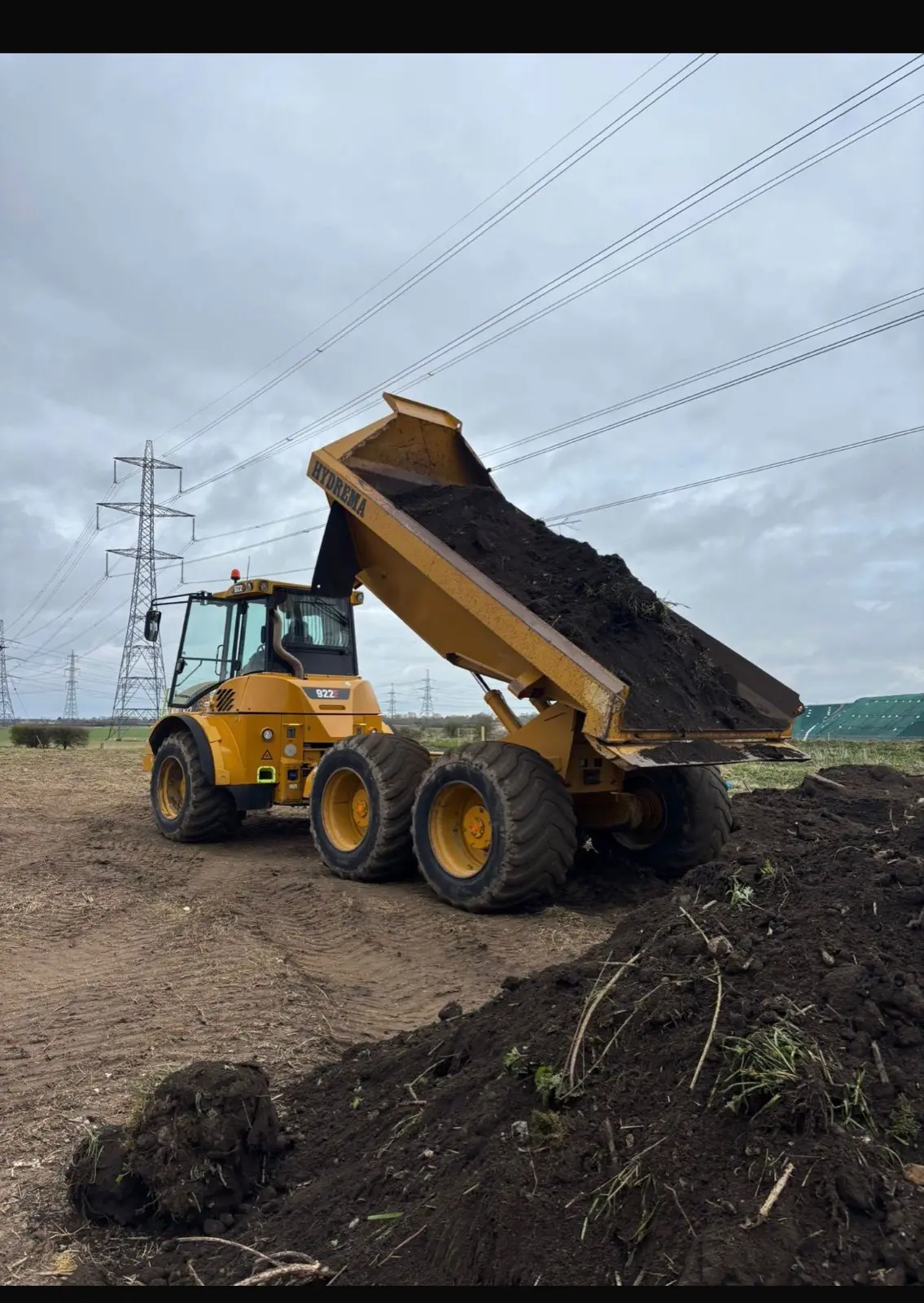 Articulated dumper tipping topsoil on site
